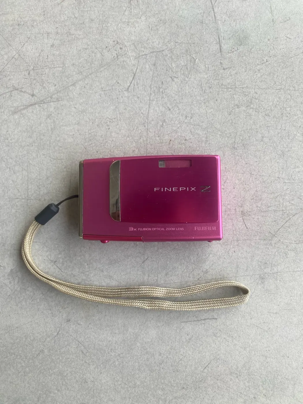 Pink Fujifilm FinePix Z compact camera with a beige wrist strap